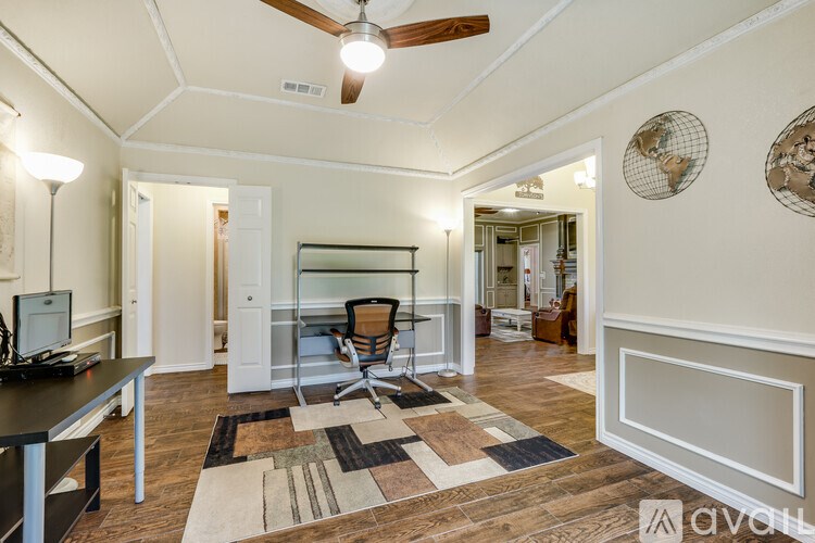 A room with a ceiling fan and a desk with a chair.
