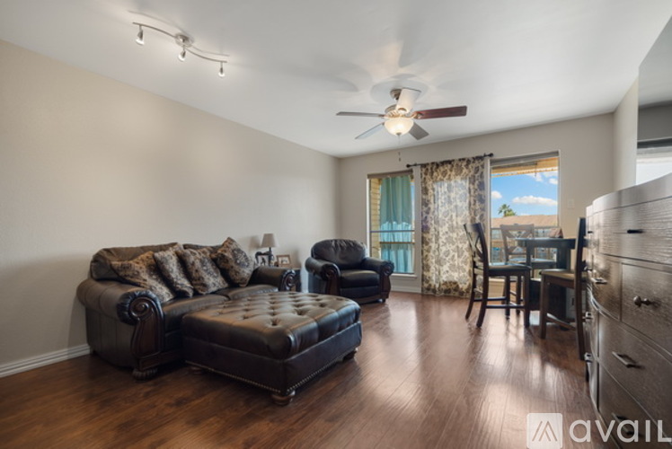 A living room with a black leather couch and a ceiling fan.