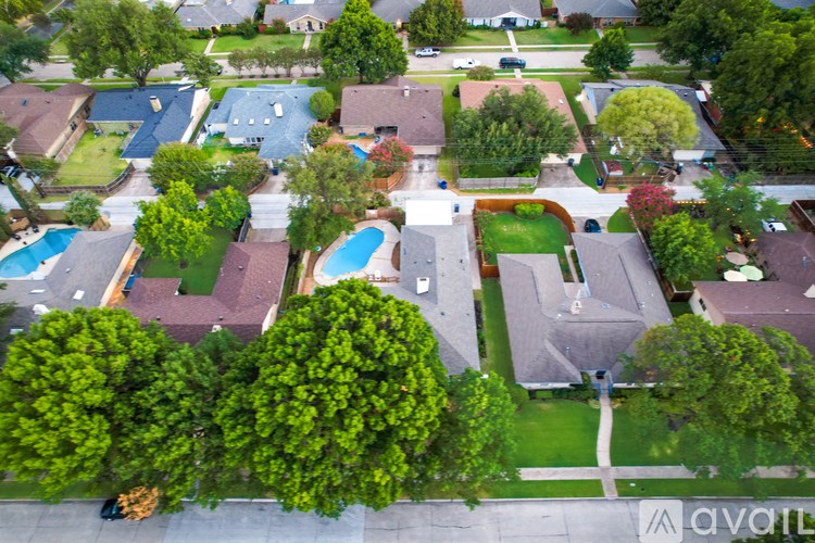 A bird's eye view of a suburban neighborhood with houses, trees, and a pool.