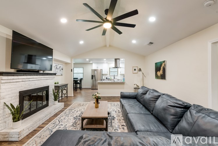 A modern living room with a black leather sofa and a fireplace.