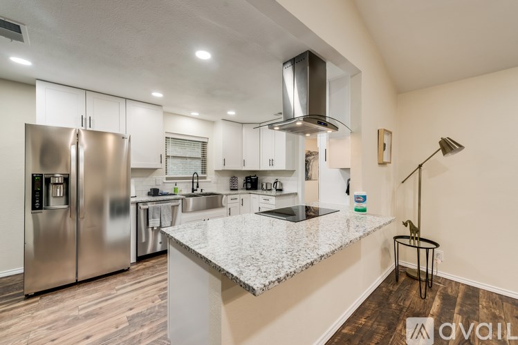 A modern kitchen with stainless steel appliances and a marble countertop.