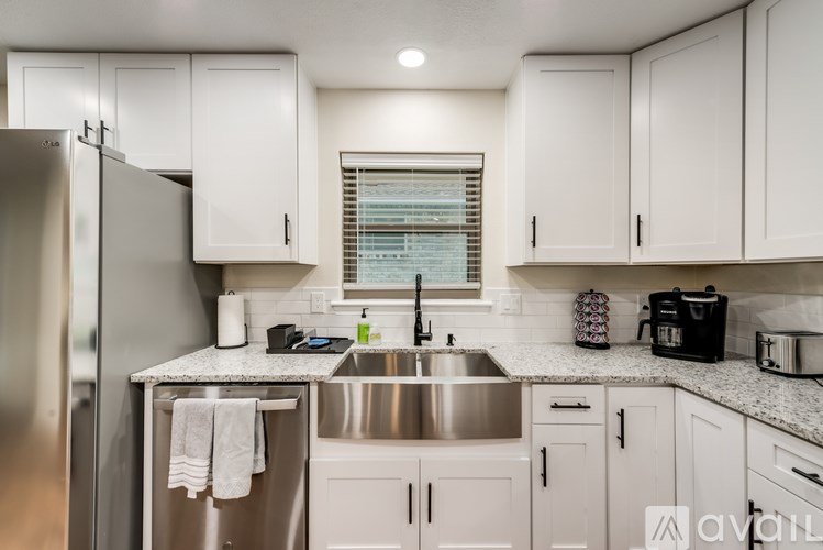 A kitchen with white cabinets and a stainless steel refrigerator.