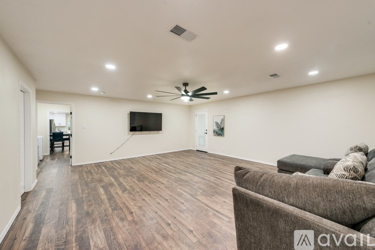 A spacious living room with a brown couch and a ceiling fan.