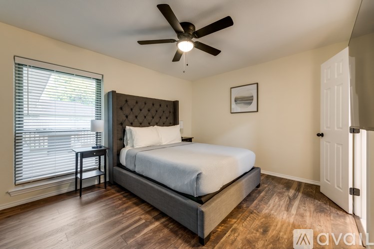 A bedroom with a bed, a table, and a ceiling fan.