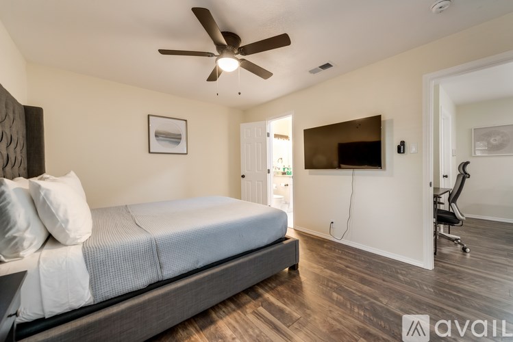 A bedroom with a bed, a chair, and a ceiling fan.