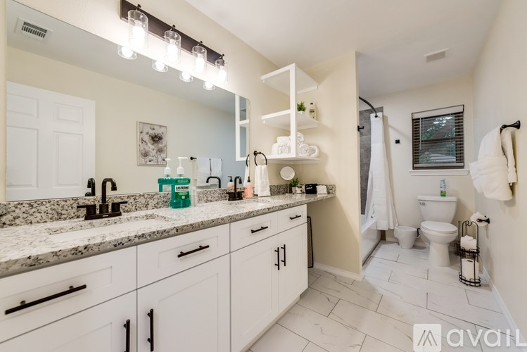 A bathroom with a marble countertop and white cabinets.