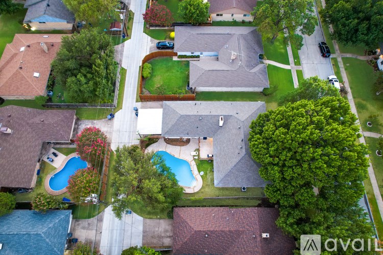 A bird's eye view of a neighborhood with houses, a pool, and a tree.