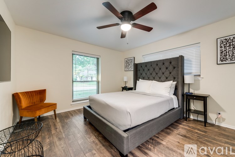 A bedroom with a large bed, a chair, and a ceiling fan.