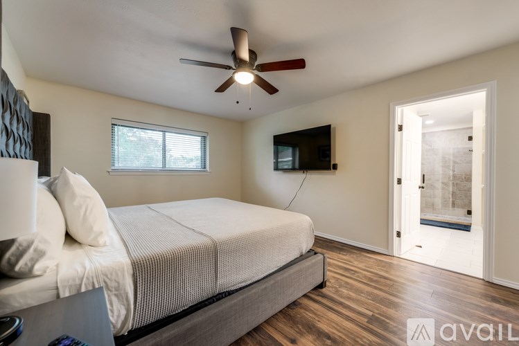 A bedroom with a bed, a ceiling fan, and a television.