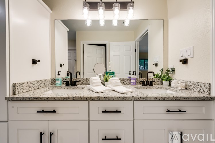 A bathroom with a marble countertop and a large mirror above it.
