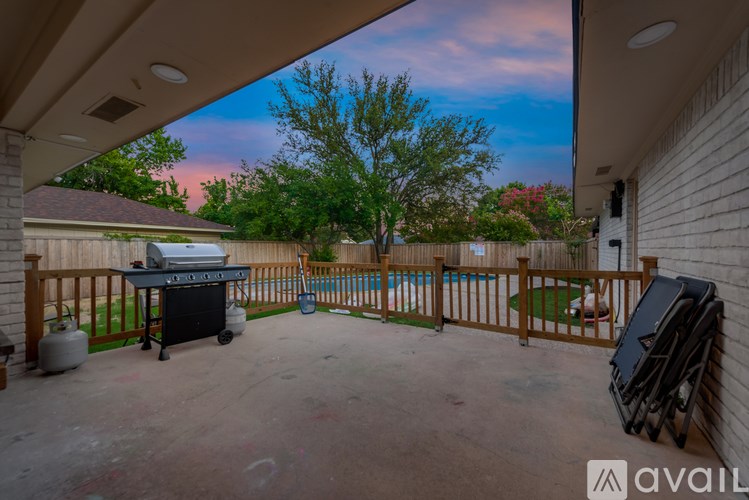 A patio with a grill and a pool in the background.