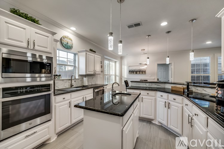 A modern kitchen with white cabinets and black countertops.