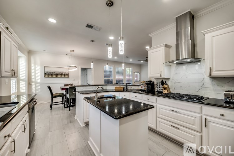 A modern kitchen with white cabinets and black countertops.