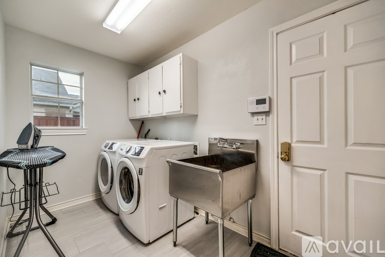 A laundry room with a washer and dryer, a sink, and a bar stool.
