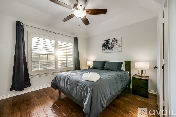 A bedroom with a bed, nightstand, and a ceiling fan.