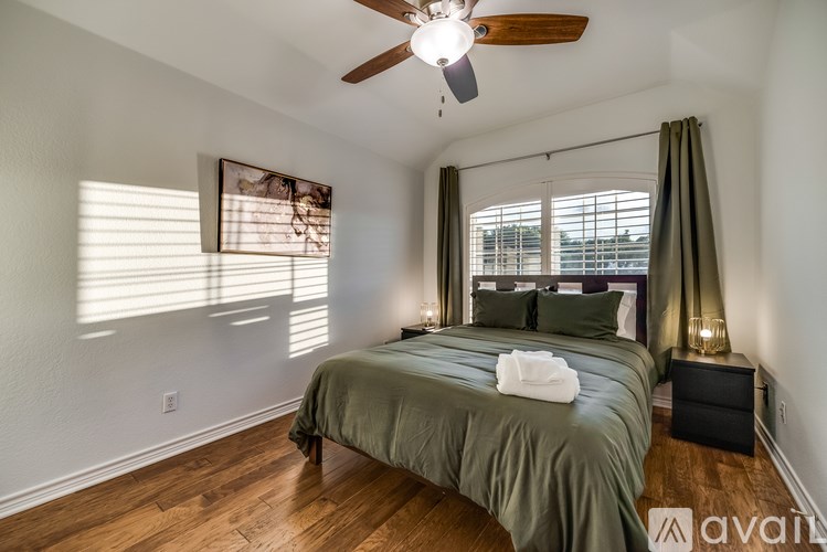 A bedroom with a bed, a ceiling fan, and a window with blinds.