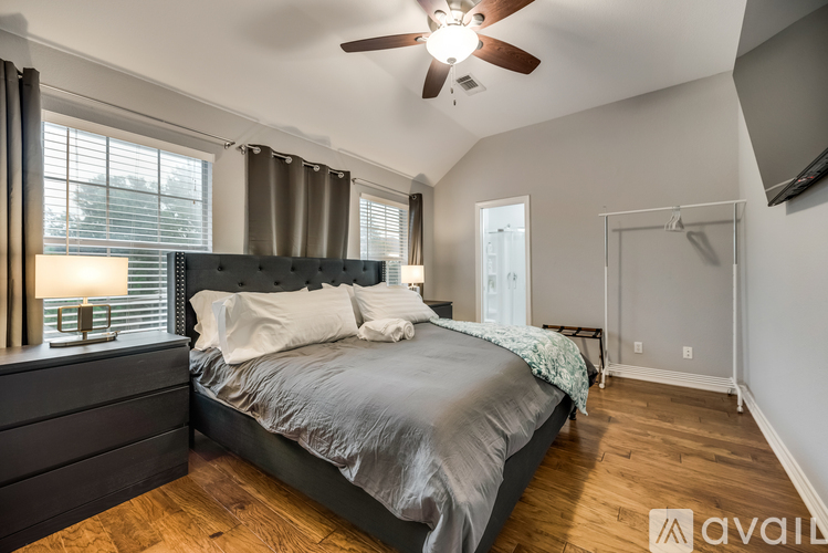 A bedroom with a large bed and a ceiling fan.