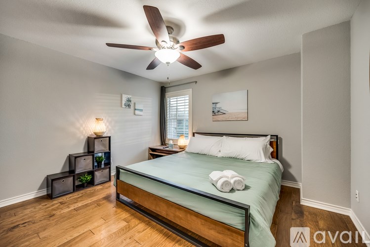 A bedroom with a bed, a ceiling fan, and a nightstand with a lamp.