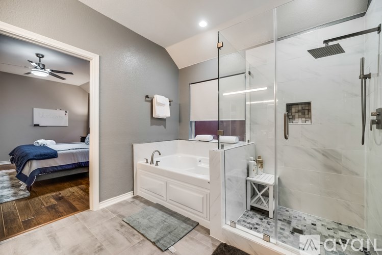 A bathroom with a walk-in shower and a bedroom area.