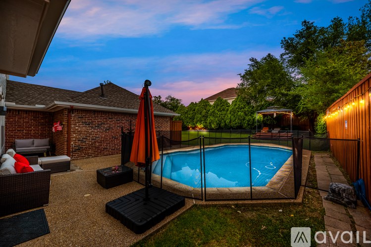A backyard with a pool and patio furniture.