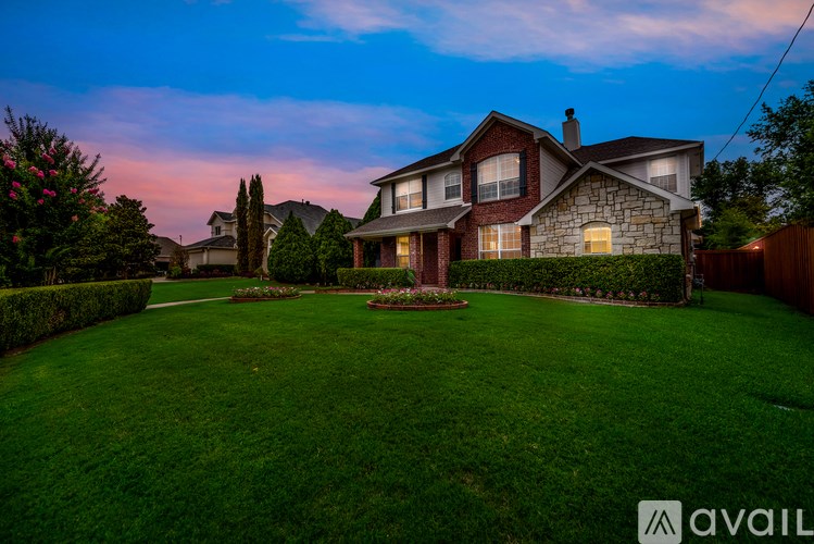 A house with a large lawn and a garden in front of it.