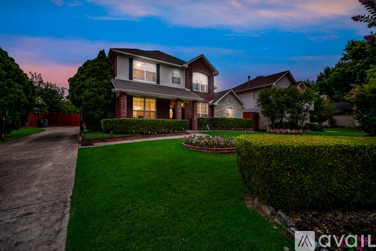 A house with a well-manicured lawn and a driveway in front.