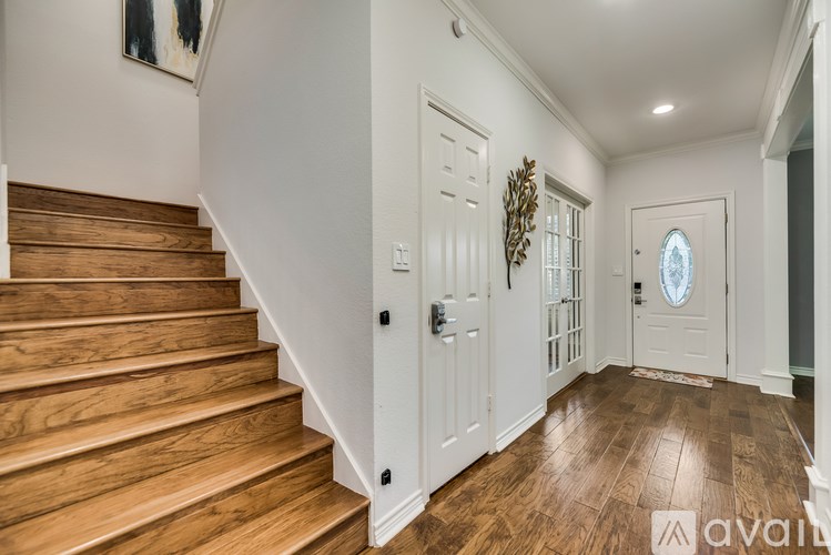 A wooden staircase leads up to a white door with a glass panel.