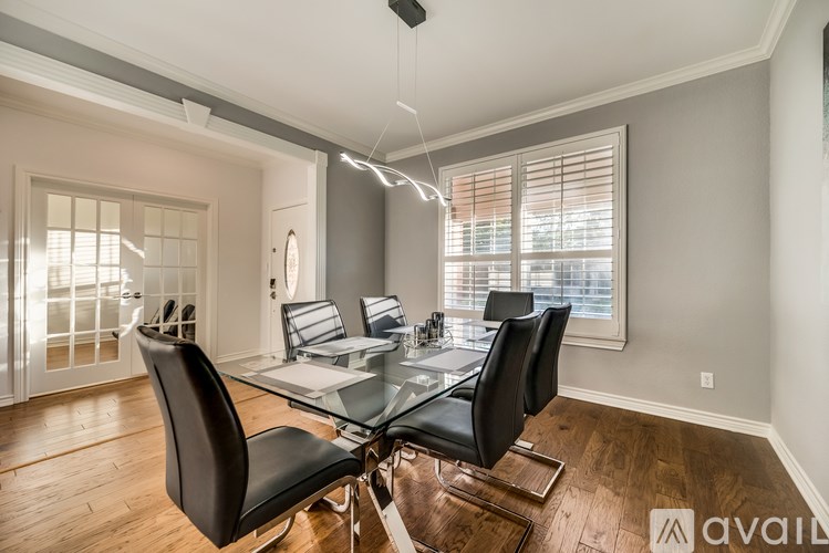 A modern dining room with a glass table and black chairs.