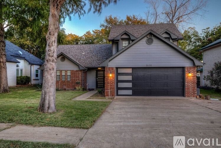 A house with a garage and a tree in front.