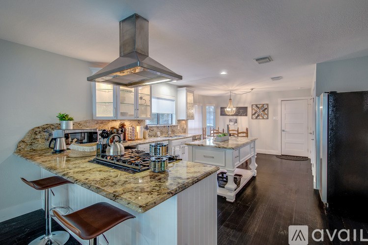 A kitchen with granite countertops and a stainless steel range hood.