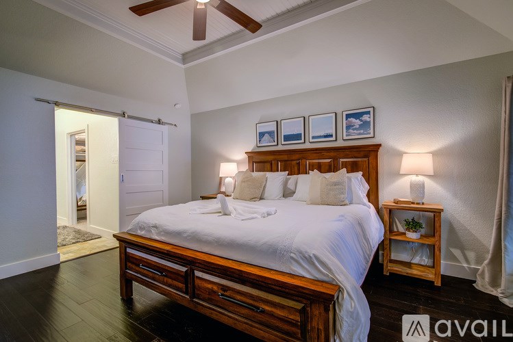 A bedroom with a bed, nightstands, and pictures on the wall.