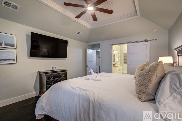 A bedroom with a large bed and a flat screen TV mounted on the wall.