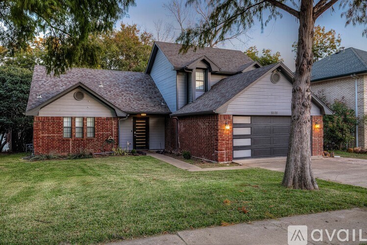 A house with a garage and a tree in front.