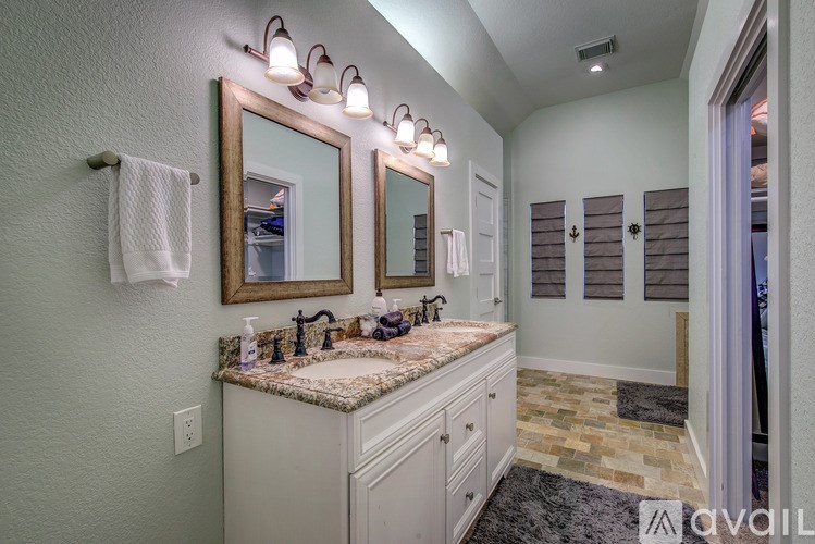 A bathroom with a marble countertop and a large mirror above it.