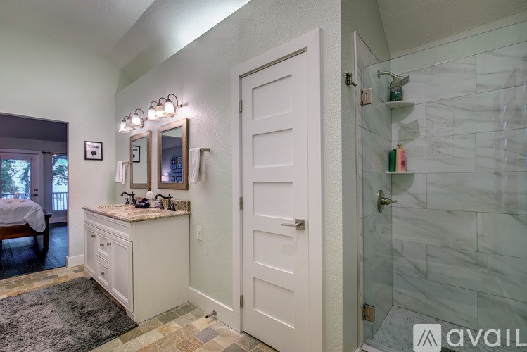 A bathroom with a white door and a marble tile shower.