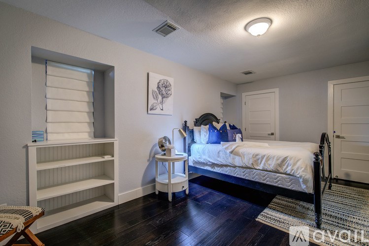 A bedroom with a bed, a nightstand, and a window with blinds.