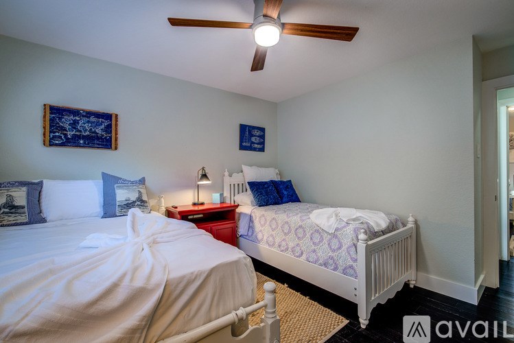 A bedroom with two beds, one with a white comforter and the other with a blue patterned comforter.