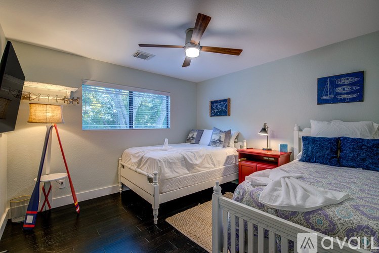 A bedroom with two beds, one with a red nightstand and the other with a white nightstand.