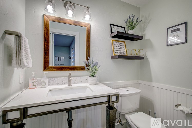 A bathroom with a mirror, sink, and toilet.