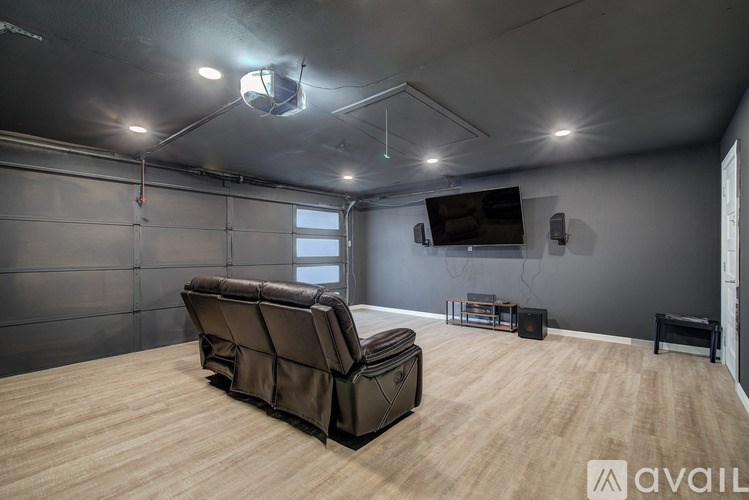 A large brown leather chair is placed in the middle of a room with wooden flooring and a grey wall.