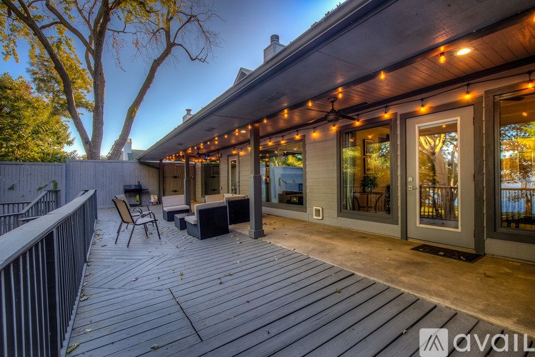 A deck with a table and chairs is lit up with string lights.