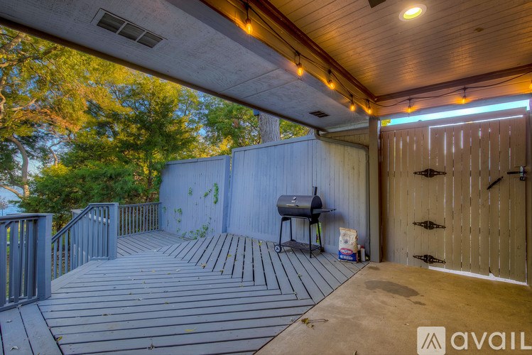A wooden deck with a grill and a table under a covered area.