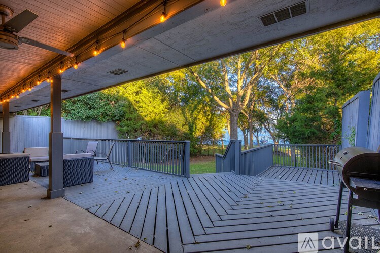 A deck with a table and chairs under a roof with lights.