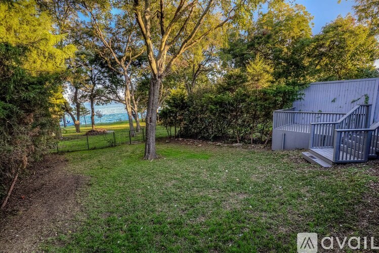A tree stands in a yard with a house in the background.