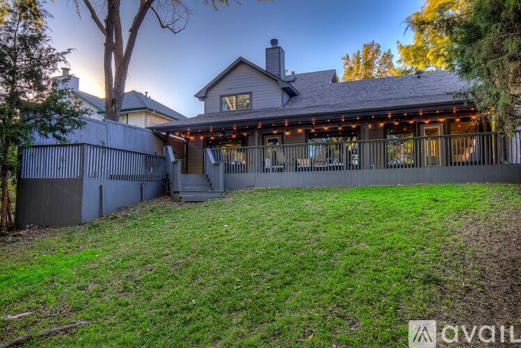 A house with a porch and a tree in front.