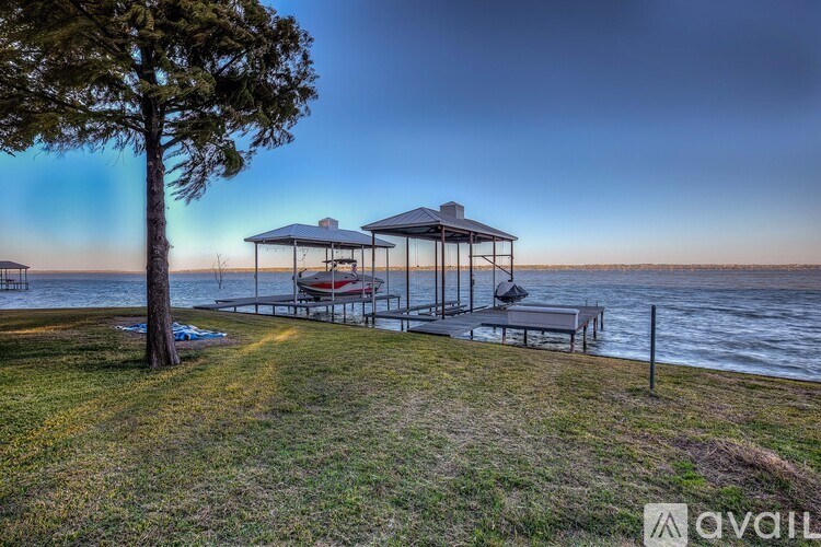 A gazebo sits on a lawn by the water's edge.