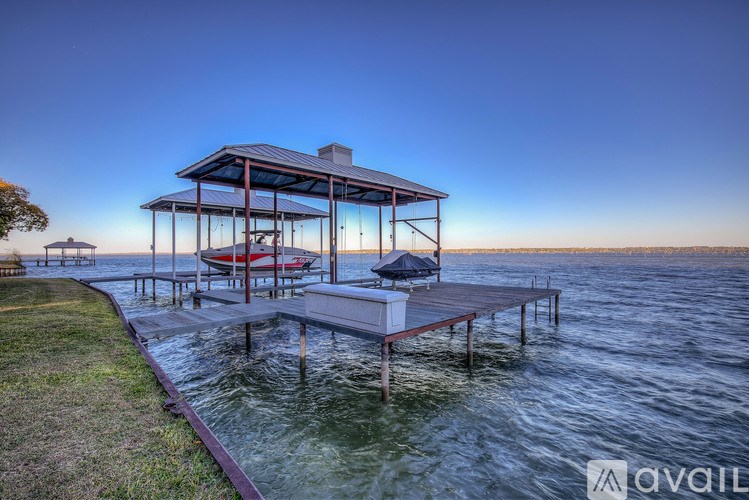 A houseboat with a deck and a hot tub sits on calm waters.