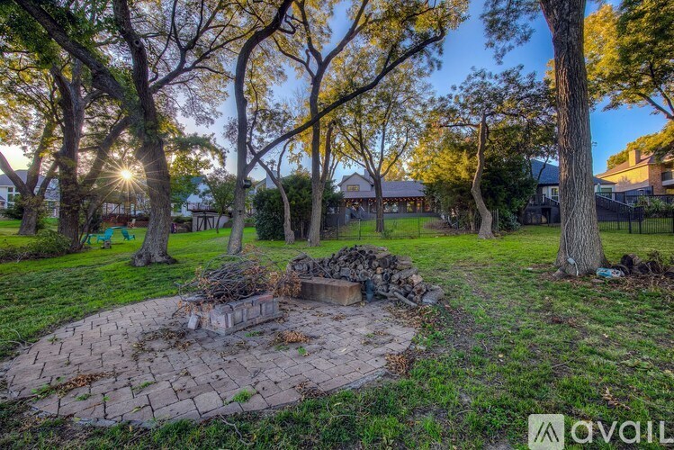A fire pit sits in the middle of a grassy area surrounded by trees.