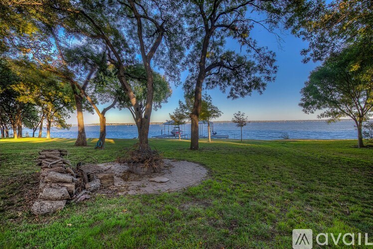 A tranquil park scene with a tree in the foreground and a body of water in the background.