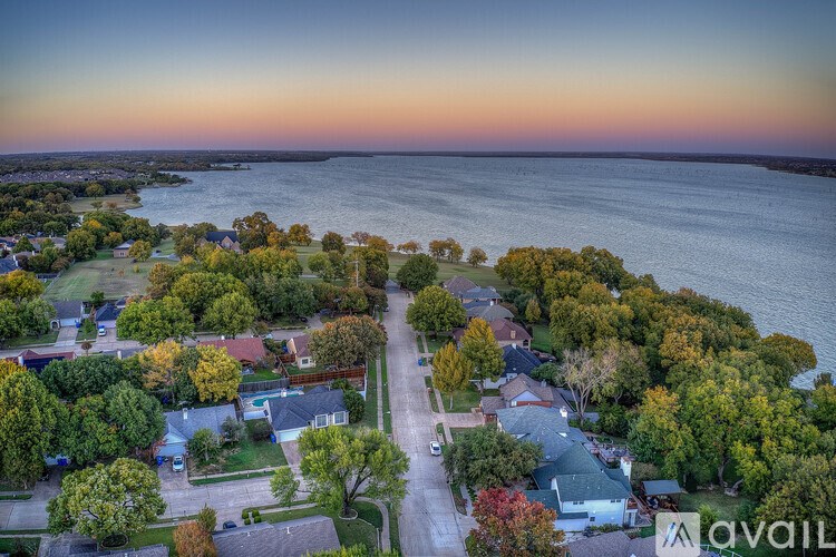 A bird's eye view of a residential area with houses, trees, and a body of water.